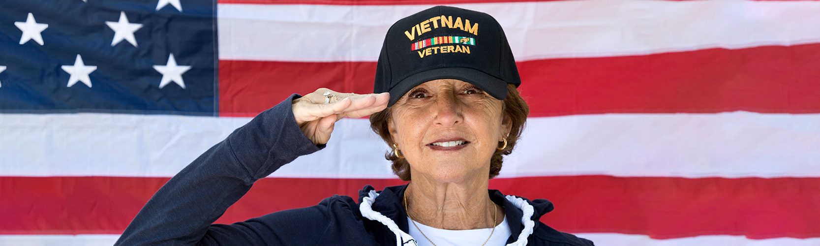 Female Vietnam Veteran in front of a U.S. flag.